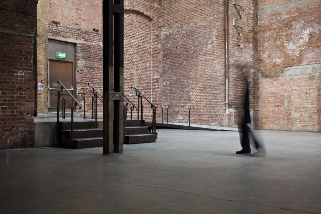 a stone building that has a sign on a brick sidewalk