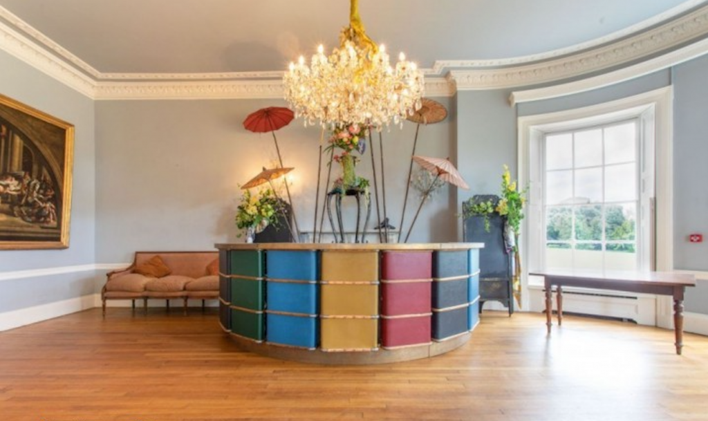 a living room filled with furniture and vase of flowers on a wooden floor