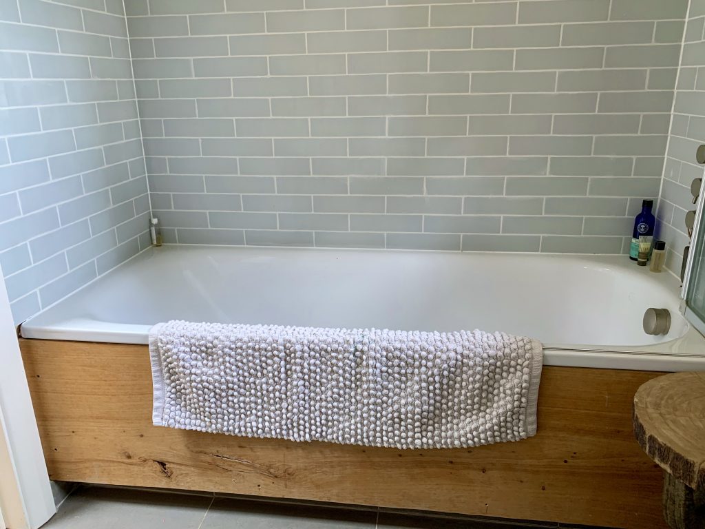 a brown tiled floor next to a tub