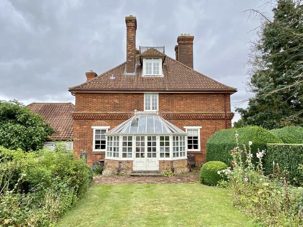 a large brick building with grass in front of a house