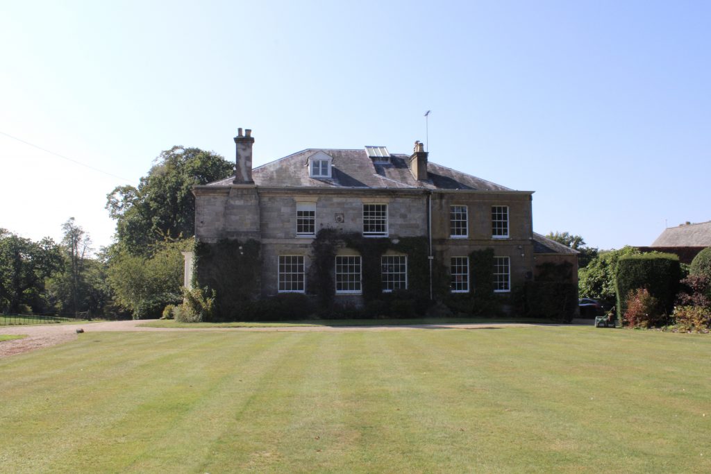a large brick building with grass in front of a house