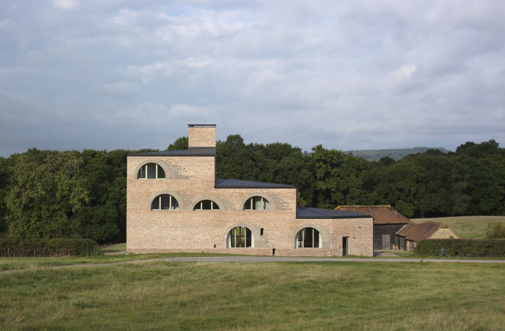 a large brick building with a tower in the middle of a field