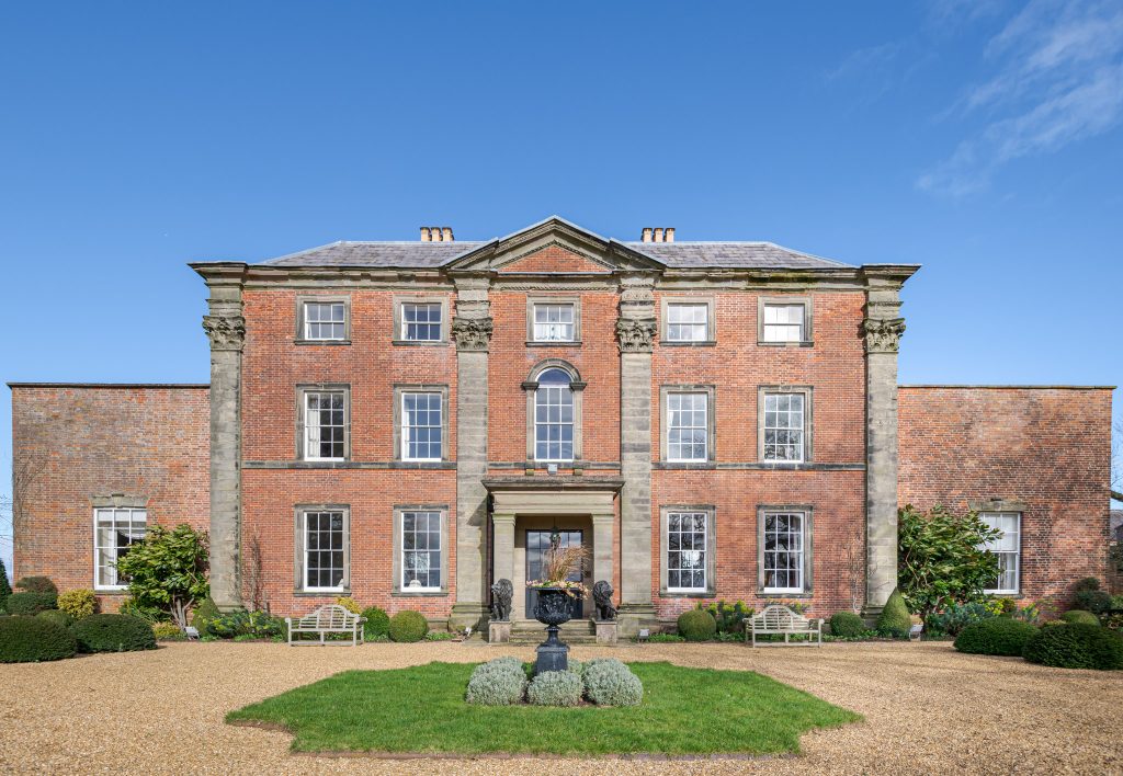 a large brick building with grass in front of a house