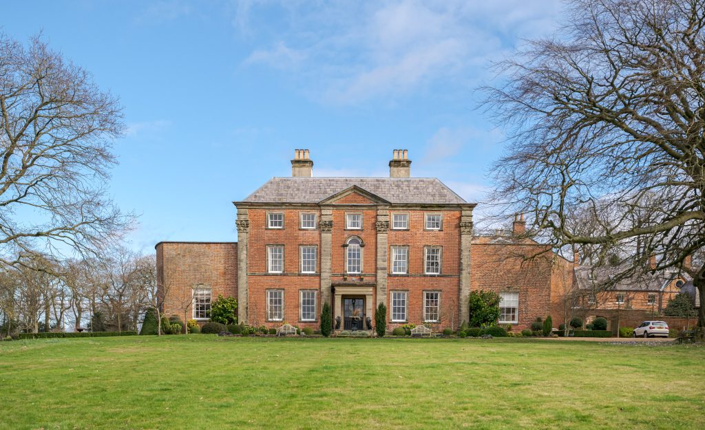 a large brick building with a grassy field