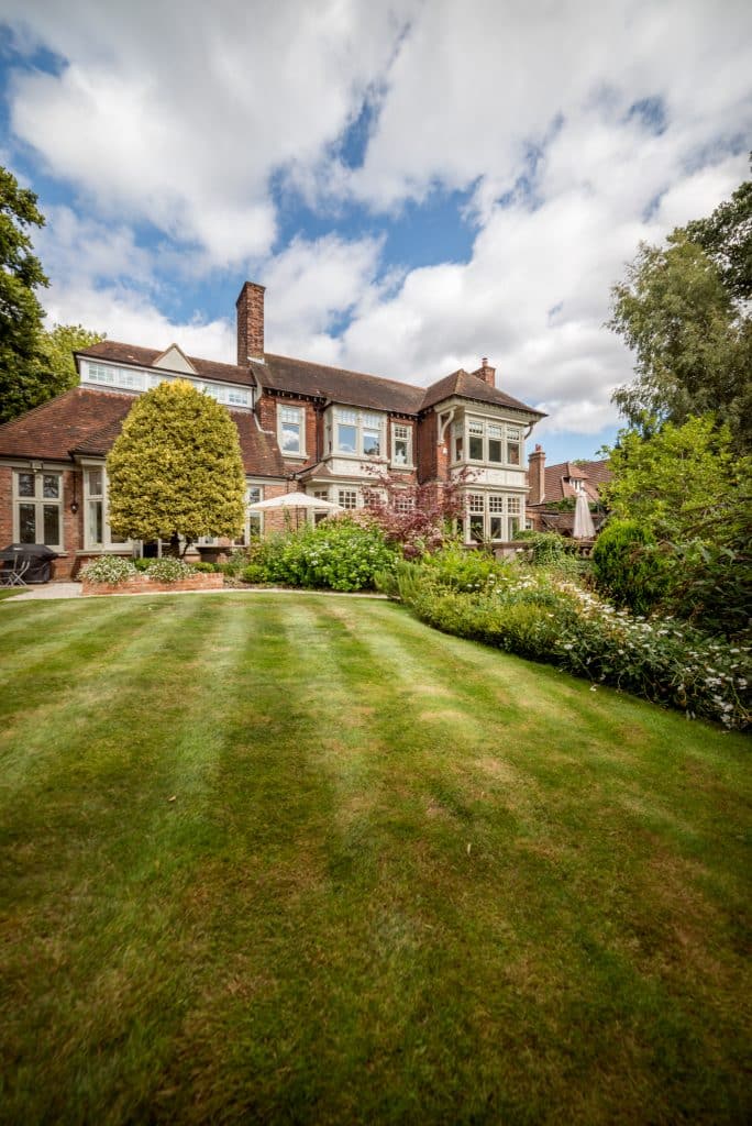 a large brick building with green grass in front of a house