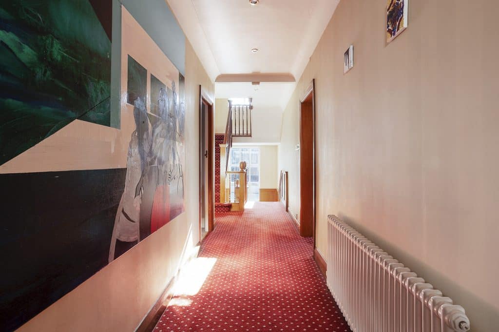 PARK LODGE9. Long-hallway-carpet-pale-walls-doorways-painting-sunlight-TV-filming-location-hire-lodge-London