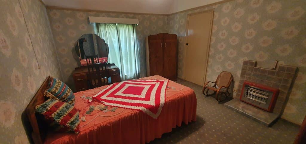 a bedroom with a bed and a chair in a room