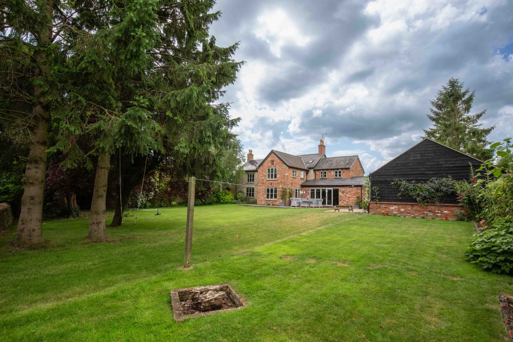 a house with a lawn in front of a lush green field