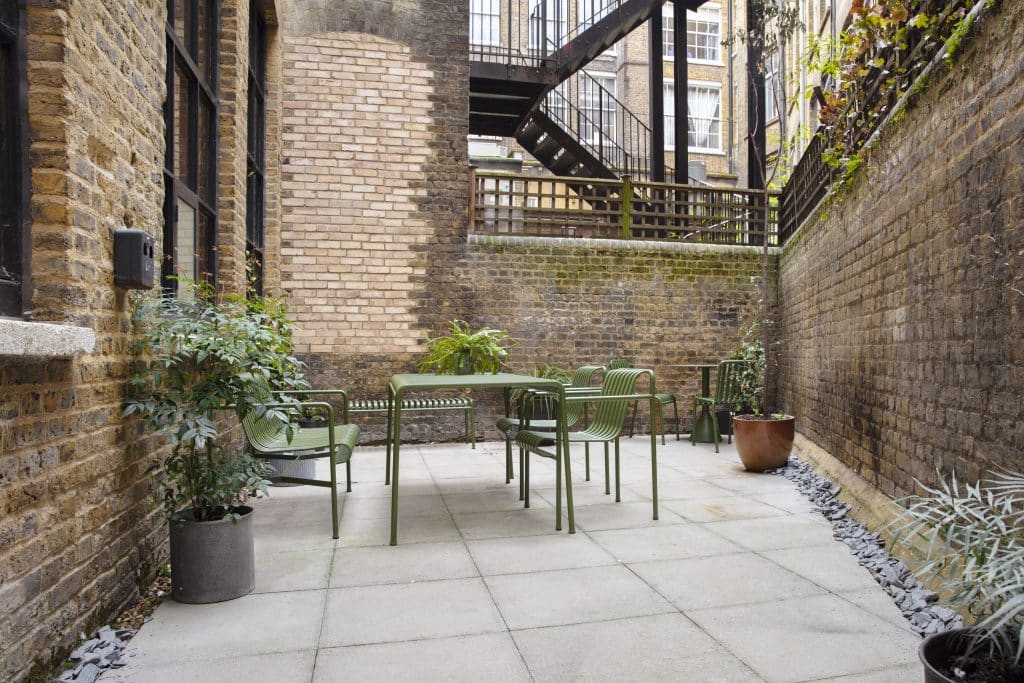 a stone building that has a bench in a garden