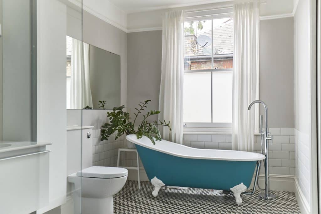 a room with a sink and a white tub sitting next to a window