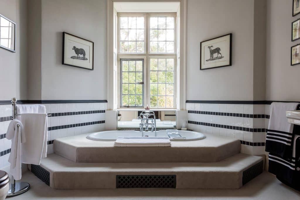 Luxury master bathroom with step up tub and black and white wall tiling
